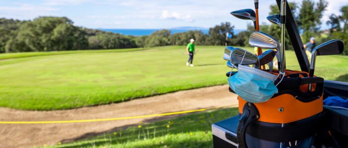 Face mask resting on golf clubs in a golf bag