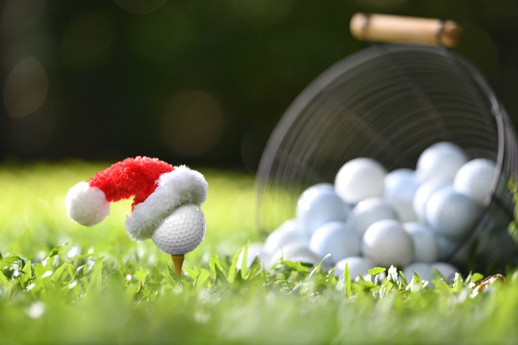 Festive golf ball on a tee with Santa Claus' hat on top