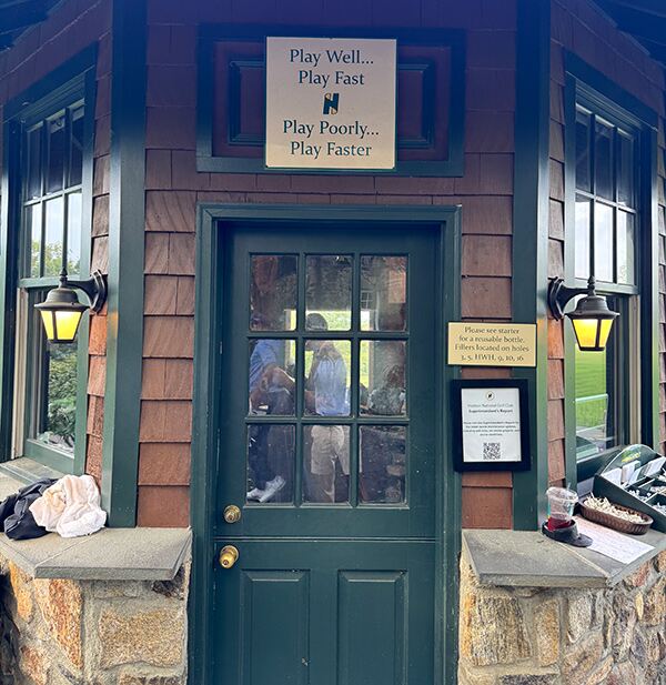 A sign at the Starter Hut reading "Play Well... Play Fast. Play Poorly... Play Faster."