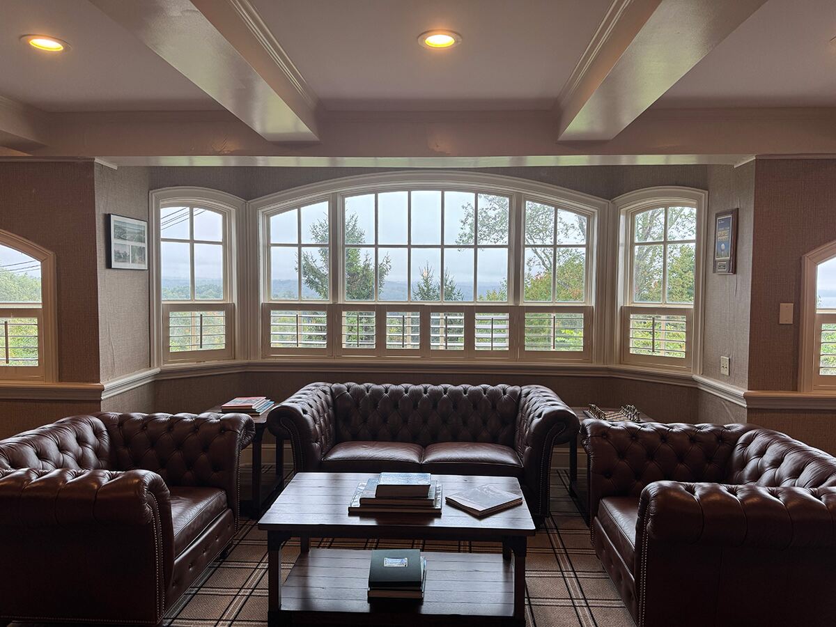 A clubhouse seating area with chesterfield sofas and a picturesque view through the window